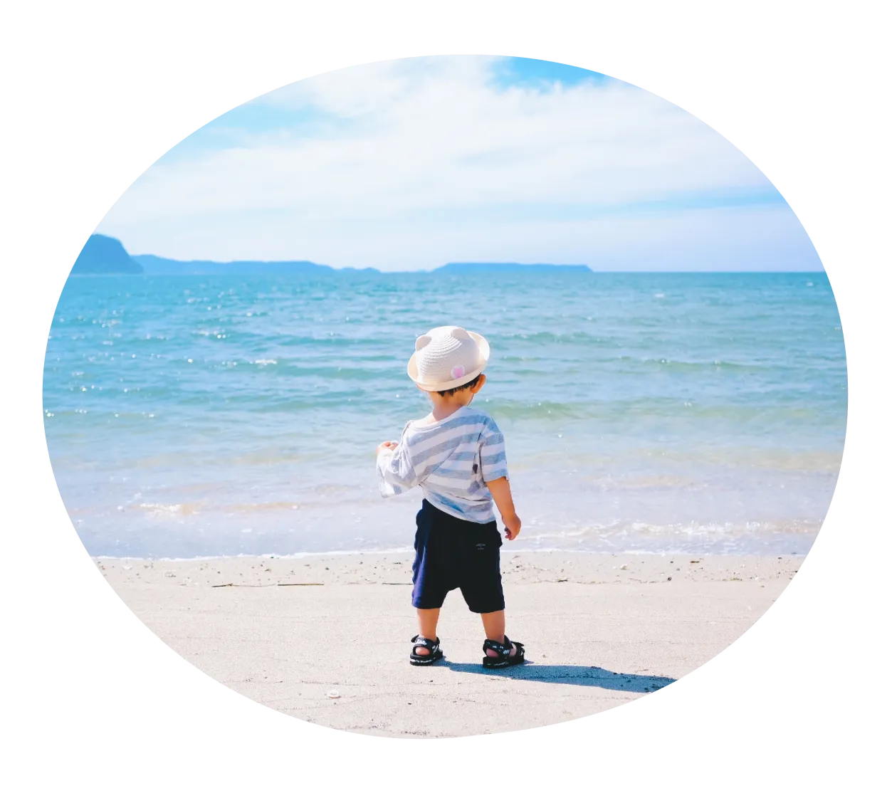 子どもが座って、両手を広げて笑っている写真