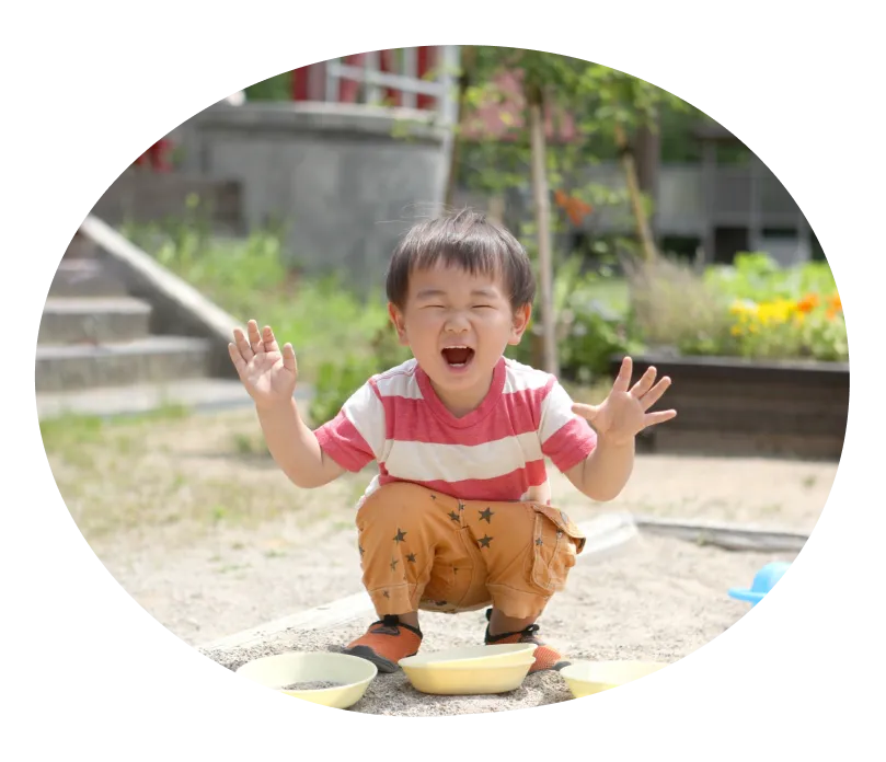 子どもが座って、両手を広げて笑っている写真