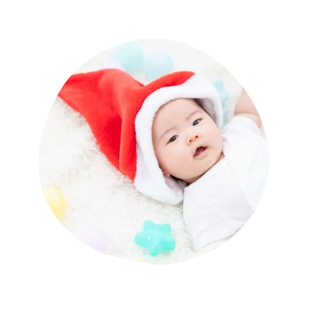サンタクロースの帽子をかぶって寝転がる赤ちゃんの写真