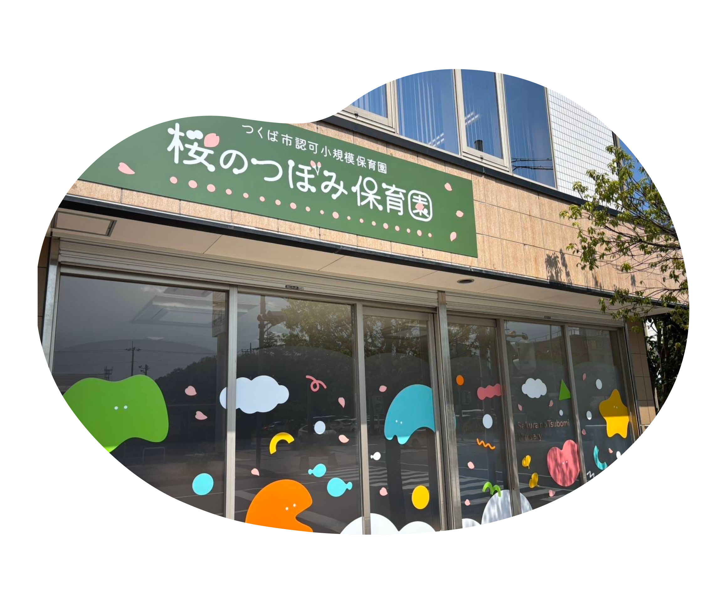 先生の膝の上で絵本を見つめる子どもと、その前で笑顔で手を叩く子どもの写真